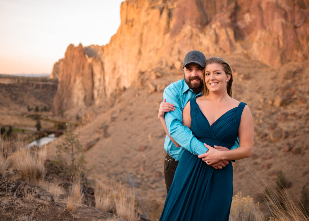 Engaged couple on top of a cliff overlooking a creek at Smith Rock State Park, Oregon.