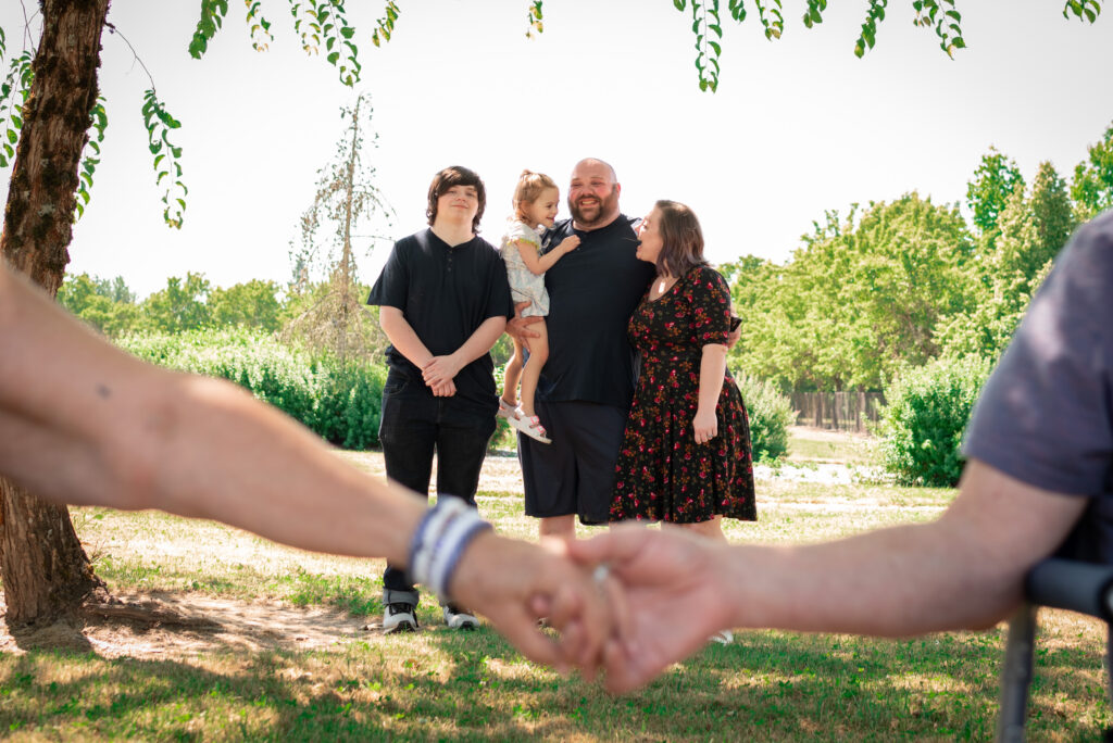 Family photo at Discovery Park in McMinnville, Oregon, with the family in focus and grandparents holding hands out of focus in the foreground.