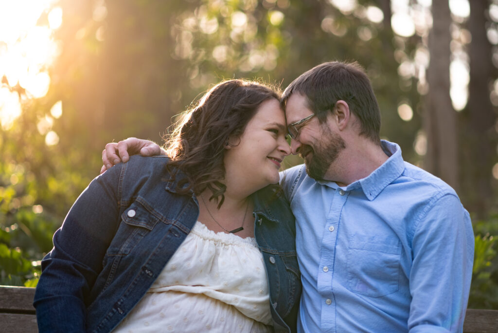 Engagement couple posing in the lush greenery of Hendricks Park, Eugene, Oregon, basking in the golden glow of the sun. 