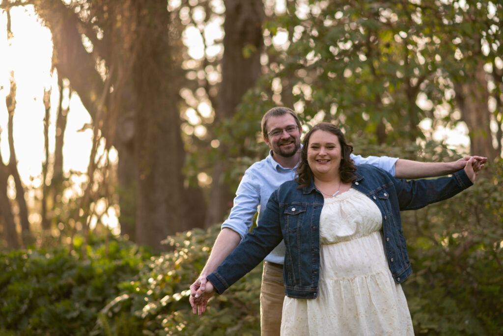 Engagement couple posing in the lush greenery of Hendricks Park, Eugene, Oregon, smiling and holding hands.